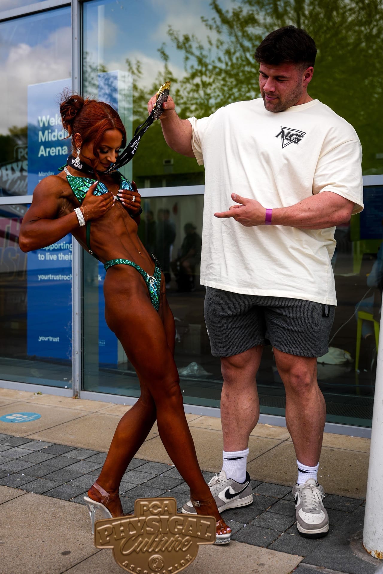 Joey Farrell handing Hannah Metcalfe a medal outside a competition venue