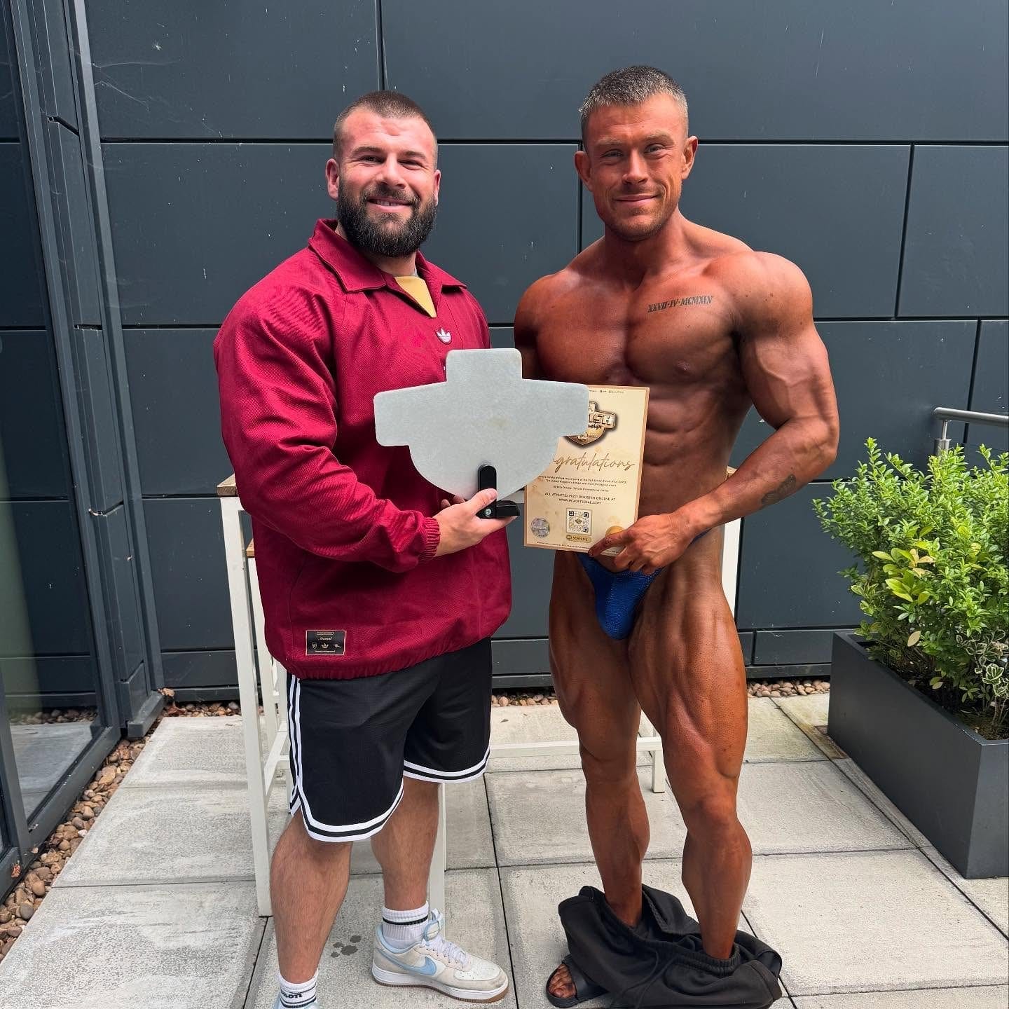A ProFlow Physiques client in contest condition outside the venue, holding the award and certificate they were presented with.